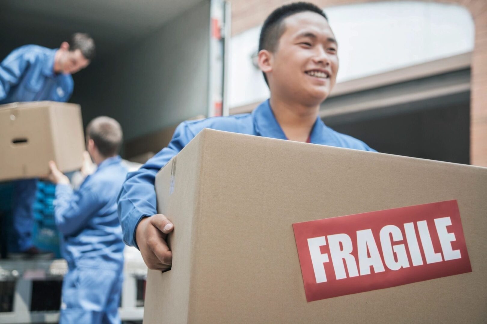 Movers unloading a moving van and carrying a fragile box